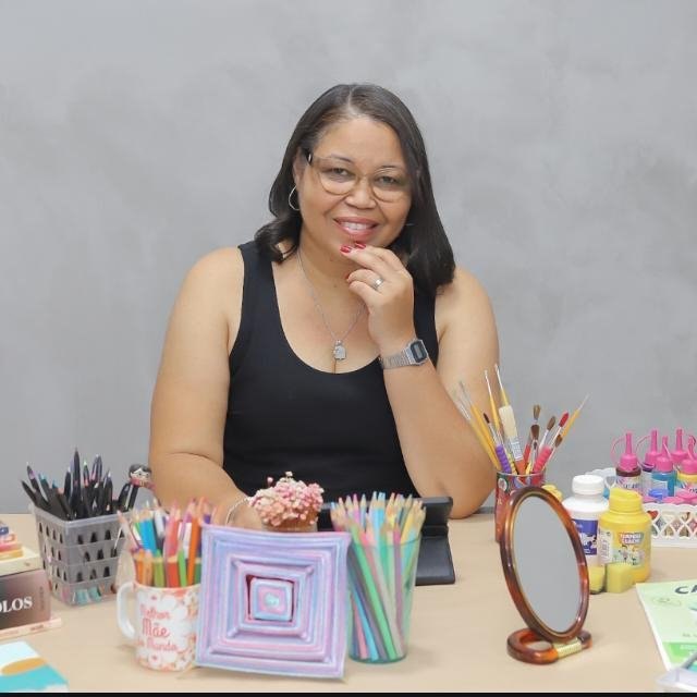Jane Carla em seu ateliê, com pincéis e materiais de arte